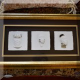 A36. Signed paper relief of 3 African heads. Gold and black paint embellishments. Frame: 13”h x 23”w